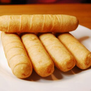 Golden brown breadsticks arranged on a white plate, perfect for meal time.